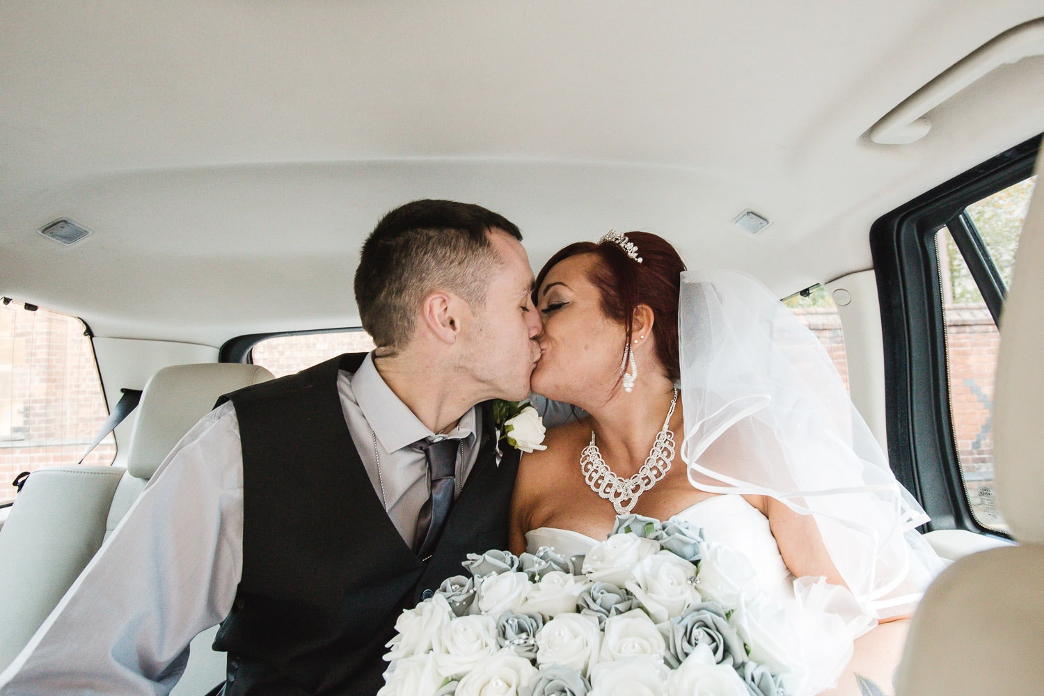 newlywed couple kissing in the back of a car