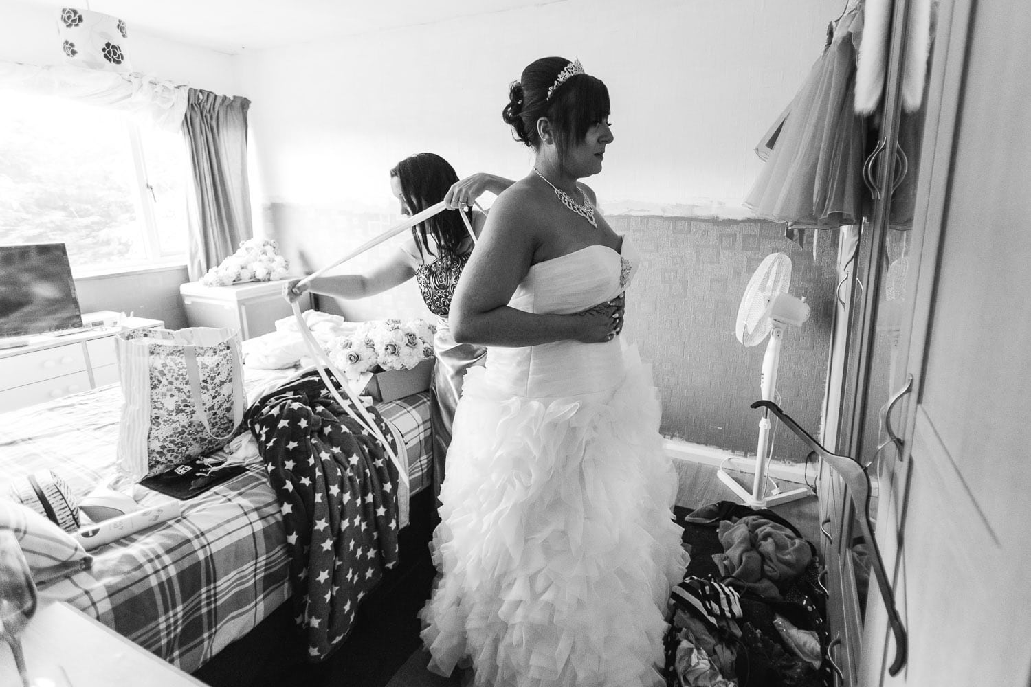 maid of honour helps the bride to put on her wedding dress