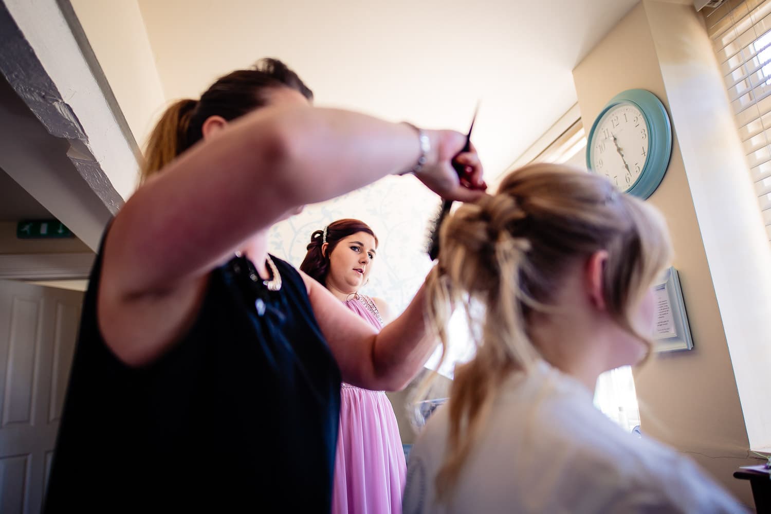 Warwick House Wedding Photography captures bridesmaid looking at bride during hair preparations