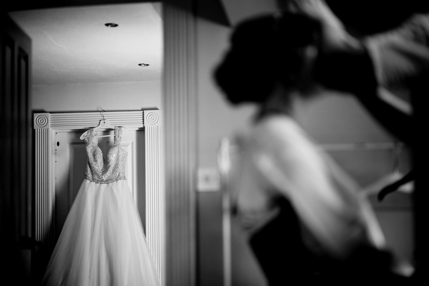bride having make up applied with wedding dress in the background by Warwick House Wedding Photography